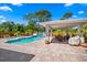 View of the sparkling pool, outdoor dining area, and lounge chairs set against the backdrop of a lush tropical backyard at 5603 Ravenwood Dr, Sarasota, FL 34243