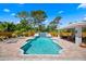 The sparkling pool features a waterfall, surrounded by brick pavers, lounge chairs, and a covered area for entertaining at 5603 Ravenwood Dr, Sarasota, FL 34243