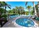 Relaxing community pool and hot tub surrounded by lush landscaping and lounge chairs under a sunny, blue sky at 564 Lakeside Dr # 564, Bradenton, FL 34210
