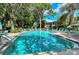 Community swimming pool with a brick paver deck lined with lounge chairs and lush landscaping and mature trees at 564 Lakeside Dr # 564, Bradenton, FL 34210