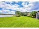 Expansive backyard featuring green grass, waterfront views, and lush palm trees at 5923 Snowy Egret Dr, Sarasota, FL 34238