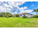 Large backyard with green grass, landscaping, and views of the home's exterior at 5923 Snowy Egret Dr, Sarasota, FL 34238