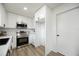 Modern kitchen with white cabinets, stainless steel appliances, and wood-look floors, with access to the bedroom at 624 Fort Duquesna Dr, Sun City Center, FL 33573
