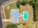 Aerial view of a home with a gray roof, a well-manicured lawn, and a refreshing, light blue swimming pool at 6698 Acmar Ct, North Port, FL 34287
