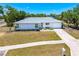 Well-maintained single-story home with a manicured lawn, landscaped garden beds, and a long driveway leading to an attached garage at 6698 Acmar Ct, North Port, FL 34287
