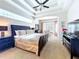 Bedroom with a ceiling fan, tray ceiling, bay window, and large bed covered in luxury bedding at 6924 Cumberland Ter, University Park, FL 34201