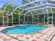 Screened-in pool with hot tub, surrounded by lush, green landscaping and patio furniture at 6924 Cumberland Ter, Bradenton, FL 34201