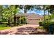 Beautiful single-story home featuring a red brick driveway, beige siding, and lush landscaping with a two-car garage at 6924 Cumberland Ter, University Park, FL 34201