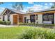 Inviting front exterior with blue door and covered porch featuring a swing and chairs, surrounded by landscaped yard at 7016 Dusty Rd, Riverview, FL 33569