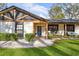 Inviting home exterior featuring a blue front door and covered porch with seating, surrounded by lush landscaping at 7016 Dusty Rd, Riverview, FL 33569