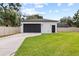 View of detached two-car garage with black garage door, adjacent yard, and partial driveway at 7016 Dusty Rd, Riverview, FL 33569