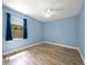 This blue bedroom features a ceiling fan, hardwood floors, a window letting in sunlight, and blue curtains at 7659 Trillium Blvd, Sarasota, FL 34241