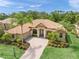 Charming home with a terracotta tile roof, paver driveway, lush landscaping, and manicured lawn at 7659 Trillium Blvd, Sarasota, FL 34241