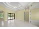 A spacious living room with tile flooring, tray ceilings, and sliding doors to the outdoor pool area at 7659 Trillium Blvd, Sarasota, FL 34241