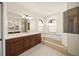 Bright main bathroom with wooden cabinets, double sinks, a soaking tub, and walk-in shower at 7659 Trillium Blvd, Sarasota, FL 34241