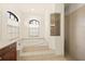 This main bathroom features an elevated soaking tub with tile surround, a walk-in shower, and two arched windows at 7659 Trillium Blvd, Sarasota, FL 34241