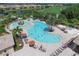 Aerial view of the community pool with lounge chairs and clear blue water, surrounded by lush landscaping and trees at 8603 River Preserve Dr, Bradenton, FL 34212