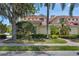 Exterior view of a well-maintained home with a red tile roof, lush landscaping and large trees at 927 River Basin Ct # 201C, Bradenton, FL 34212