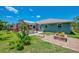This backyard has a covered patio with seating, well manicured landscaping, and a brick fire pit at 9321 New Martinsville Ave, Englewood, FL 34224