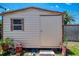 Backyard storage shed featuring a metal door and single window with surrounding landscaping at 9321 New Martinsville Ave, Englewood, FL 34224