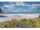 Picturesque beach scene with volleyball nets and calm ocean waters, framed by colorful vegetation and a partly cloudy sky at 1038 Contento St, Sarasota, FL 34242