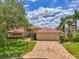 Charming single-Gathering home with a red-tiled roof, brick driveway, and tropical landscaping at 1038 Contento St, Sarasota, FL 34242