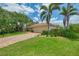 Beautiful home with brick driveway and well-manicured lawn with tropical plants and trees at 1038 Contento St, Sarasota, FL 34242