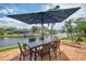 Outdoor dining area featuring a large umbrella, waterfront views and lounge chairs on the pool deck at 1038 Contento St, Sarasota, FL 34242
