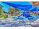 Vibrant beach playground featuring a blue play structure with slides, set against a backdrop of lush trees and clear skies at 1038 Contento St, Sarasota, FL 34242