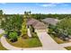 Landscaped single-story home with driveway, surrounded by mature trees and lush greenery under a clear blue sky at 11634 Piedmont Park Xing, Bradenton, FL 34211