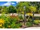 Lush front yard with flowering shrubs, palm trees, mature shade trees, and a vintage-style lamp post at 11634 Piedmont Park Xing, Bradenton, FL 34211