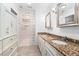 Bathroom with double sinks, granite countertop, modern lighting, and a tiled walk-in shower with glass block accents at 1502 Water Oak S Way, Bradenton, FL 34209