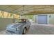 Charming carport featuring a vintage car, with a tiled ground and surrounded by lush greenery, providing stylish covered parking at 1910 Datura St, Sarasota, FL 34239