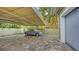 Covered carport with a classic car parked on a tiled surface and surrounded by lush greenery and palm trees at 1910 Datura St, Sarasota, FL 34239