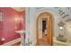 Hallway featuring an archway with a wooden door, access to a pink powder room and stairway at 1910 Datura St, Sarasota, FL 34239