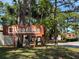 Wooden Woodlake community sign surrounded by trees, indicating a welcoming and private neighborhood entrance at 2058 Sunset Point Rd # 11, Clearwater, FL 33765