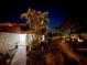 Inviting townhome exterior with lush landscaping, mature palm trees, and a well-lit walkway to the front door at 2058 Sunset Point Rd # 11, Clearwater, FL 33765