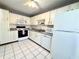 Charming kitchen with white cabinetry, appliances, and white tile flooring at 2058 Sunset Point Rd # 11, Clearwater, FL 33765
