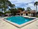 Community pool with clear blue water, surrounded by ample seating and lush landscaping at 2058 Sunset Point Rd # 11, Clearwater, FL 33765