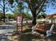 Street view featuring Woodlake community sign, bench, mature trees, and ample parking at 2058 Sunset Point Rd # 11, Clearwater, FL 33765