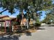 Street view featuring Woodlake community sign, bench, mature trees, and ample parking at 2058 Sunset Point Rd # 11, Clearwater, FL 33765