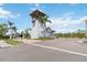 Charming community entrance featuring a white guard house with wooden accents, surrounded by lush greenery and palm trees at 230 Sapphire Lake Dr # 201, Bradenton, FL 34209
