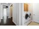 Clean hallway with dark hardwood floors, laundry area with washer and dryer, blending convenience with style at 230 Sapphire Lake Dr # 201, Bradenton, FL 34209