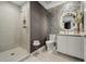 Modern bathroom featuring stylish honeycomb tiles, a round mirror, and a glass-enclosed shower at 301 Quay Commons # 1709, Sarasota, FL 34236