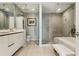 Modern bathroom featuring double sinks, walk-in shower, soaking tub, and neutral color palette at 301 Quay Commons # 1709, Sarasota, FL 34236