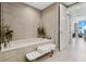 Stylish bathroom featuring a soaking tub, bench, and decorative accents, complemented by neutral tiling at 301 Quay Commons # 1709, Sarasota, FL 34236