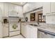 White kitchen features bright white cabinetry, stainless steel dishwasher, granite countertops and a pass through window at 3130 Ringwood Mdw # 44, Sarasota, FL 34235