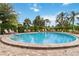 Community pool surrounded by lush tropical landscaping with tables, chairs, and umbrellas for relaxation at 3130 Ringwood Mdw # 44, Sarasota, FL 34235