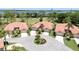 Aerial view of coordinated homes with terracotta tile roofs circling a cul-de-sac with bay views in the background at 3412 E Chelmsford Ct # 42, Sarasota, FL 34235