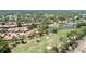 An aerial view shows houses with terracotta roofs bordering the golf course with a pond and abundant trees at 3412 E Chelmsford Ct # 42, Sarasota, FL 34235